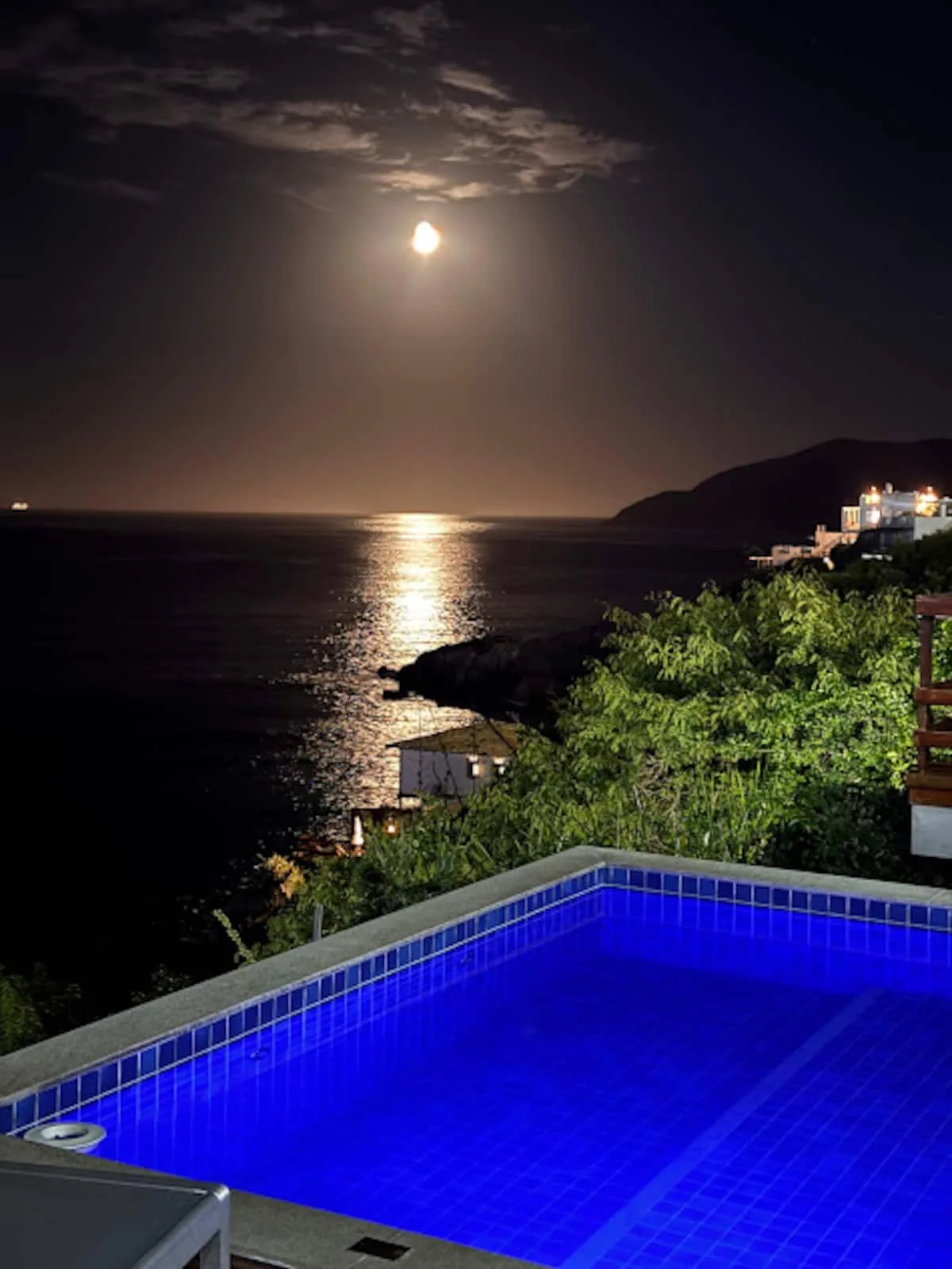 Piscina iluminada à noite com o luar sobre o mar