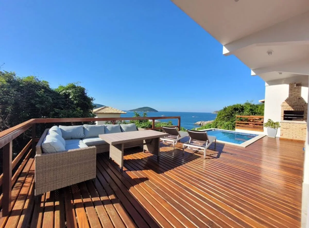 Deck de madeira com sofás ao lado da piscina e vista para o oceano